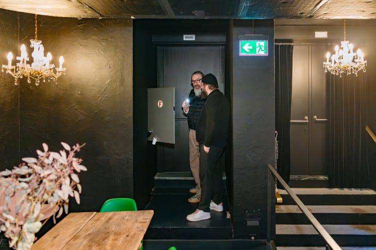 Remo Gygax und Marcel Hügel stehen vor dem Feuerlöschschlauch, der in die Wand eingelassen ist, und sprechen miteinander.