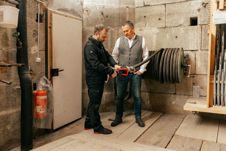 Lukas Ammann zeigt Tino Perotti auf dem Hochschiffestrich einen Feuerwehrschlauch.