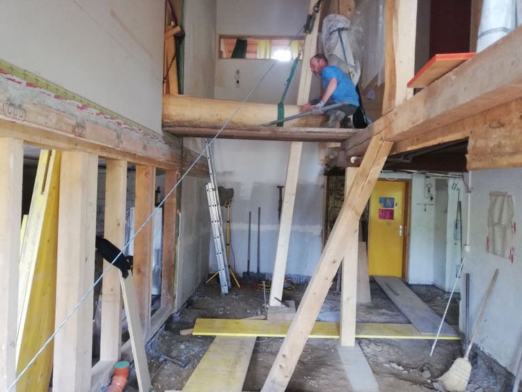 Blick ins Erd- und ins Obergeschoss des Hauses. Die Decke fehlt, ebenso wie ein Teil der Zwischenwände. Der Firstpfosten liegt horizontal im Obergeschoss.