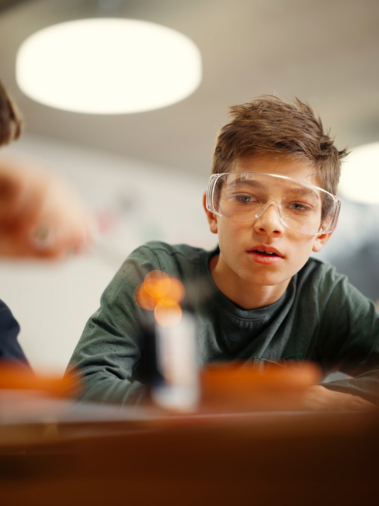 Ein Junge mit Schutzbrille schaut zu, wie Stahlwolle auf einer Batterie glüht.