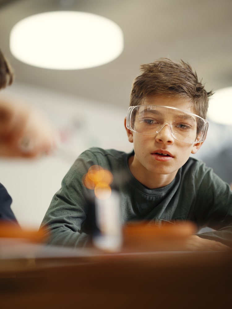 Ein Junge mit Schutzbrille schaut zu, wie Stahlwolle auf einer Batterie glüht.