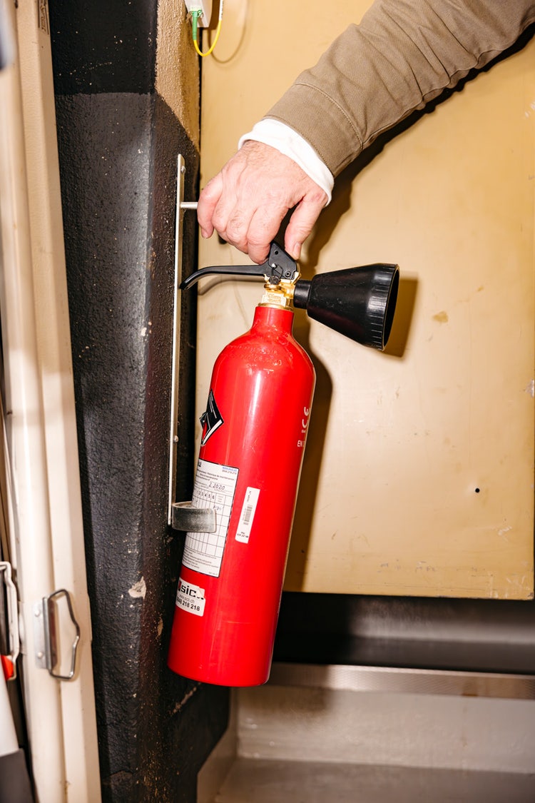 Marcel Hügel prüft das Wartungsetikett eines Handfeuerlöschers.