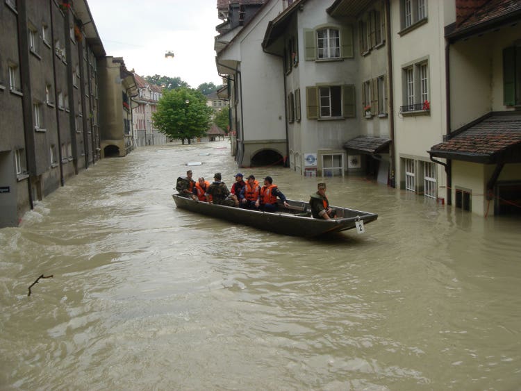In der überfluteten Gerberngasse fährt ein Boot mit sieben Mann Besatzung.