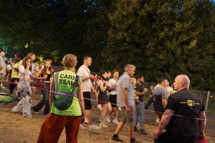 Mitarbeitende von Security und Care Team auf dem Festivalgelände, im Hintergrund Besuchende.