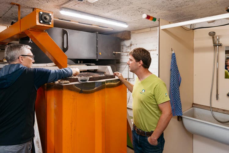 Michael Kipfer zeigt, wie Holzschnitzel in die Pyrolyseanlage gefüllt werden.