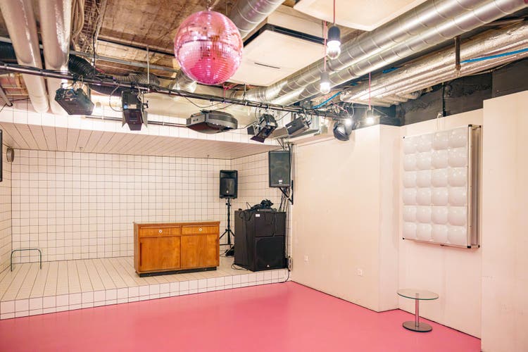 Das Fumoir hat einen rosafarbenen Boden, weisse Wände und eine Discokugel an der Decke.