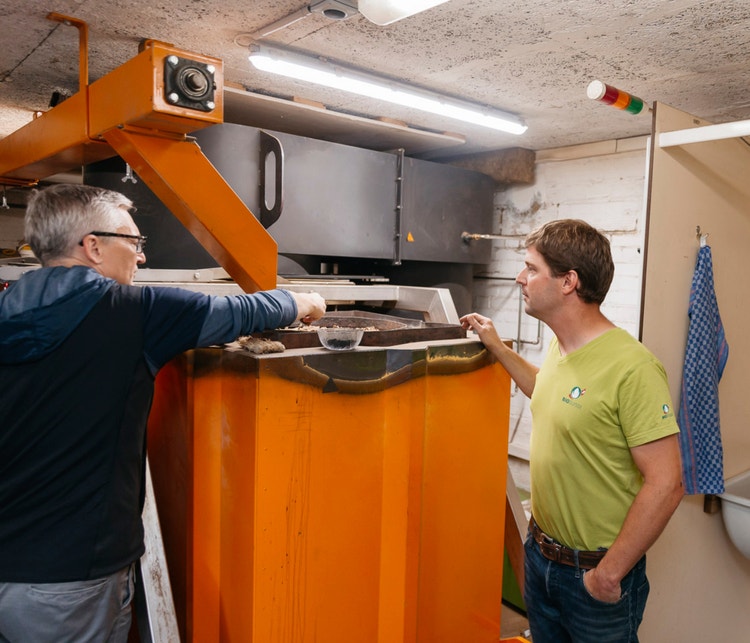 Michael Kipfer zeigt, wie Holzschnitzel in die Pyrolyseanlage gefüllt werden.