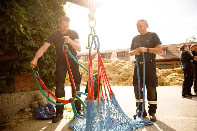 Deux pompiers préparent le filet horizontal et l’accrochent à un dispositif de levage.