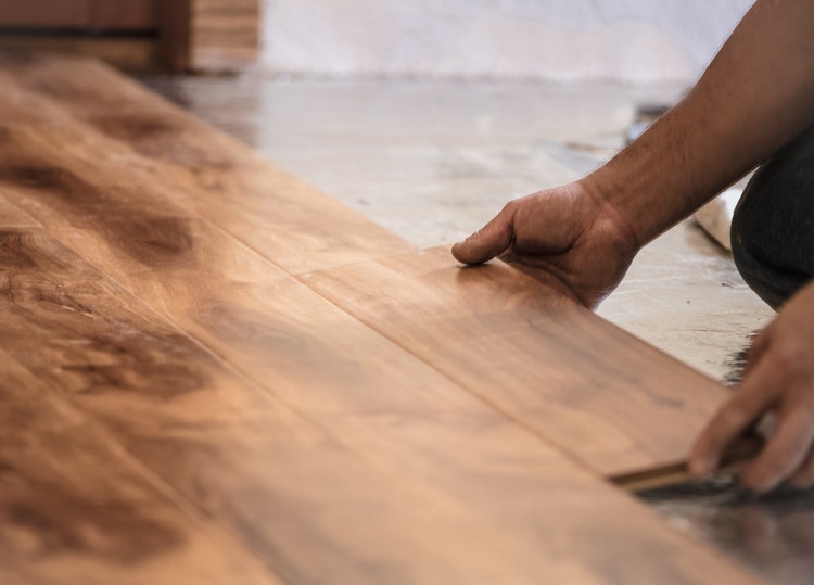 Un homme pose du parquet dans une pièce.