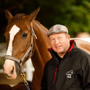 Un homme pose avec un cheval.
