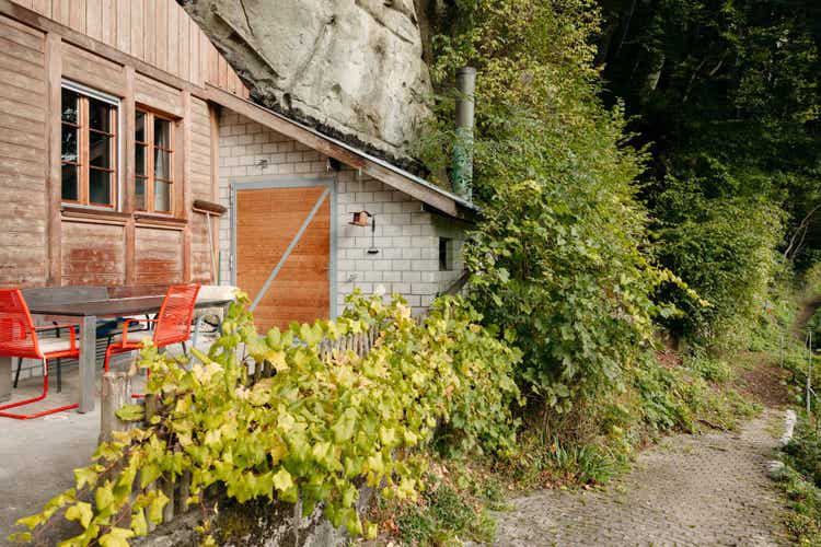 Vue latérale de la maison avec annexe en blocs de béton et porte en bois.