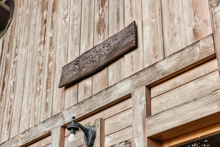 Gros plan sur la façade en bois de la maison et le nom « Fluehüsli » gravé au-dessus de la porte d’entrée.