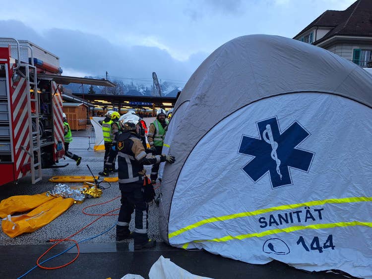Des sapeurs-pompiers aident des secouristes à monter une tente après un grave accident de la route.