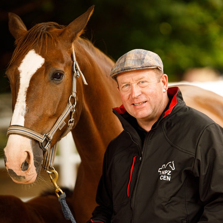Un homme pose avec un cheval.
