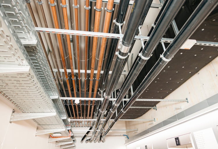 Le plafond d’un couloir est équipé de tubes de différentes hauteurs qui alimentent le bâtiment.
