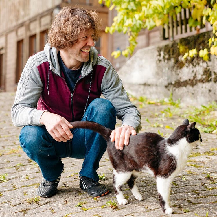 Matthias Müller caressant son chat sur la terrasse devant le Fluehüsli à Krauchthal.