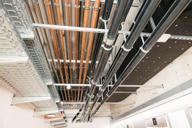 Le plafond d’un couloir est équipé de tubes de différentes hauteurs qui alimentent le bâtiment.
