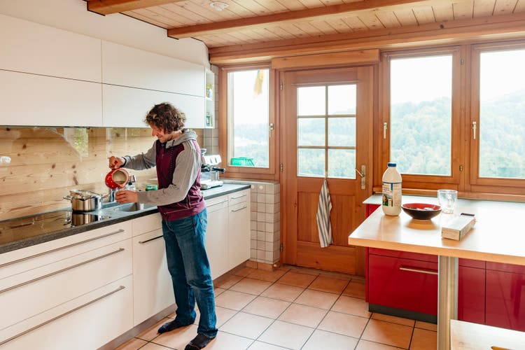 Matthias Müller dans sa cuisine ouverte et lumineuse, en train de verser du thé dans une tasse.