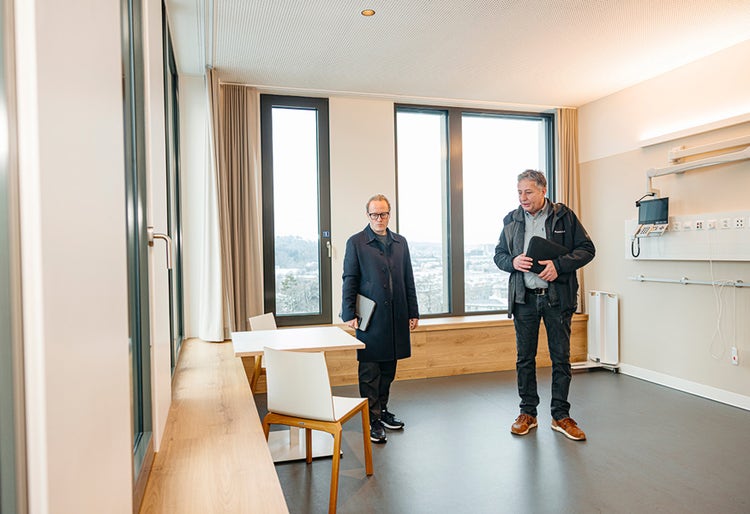 Deux hommes (Roger Kurt et Markus Wasmer) se tiennent dans une chambre de soins de la Anna-Seiler-Haus.